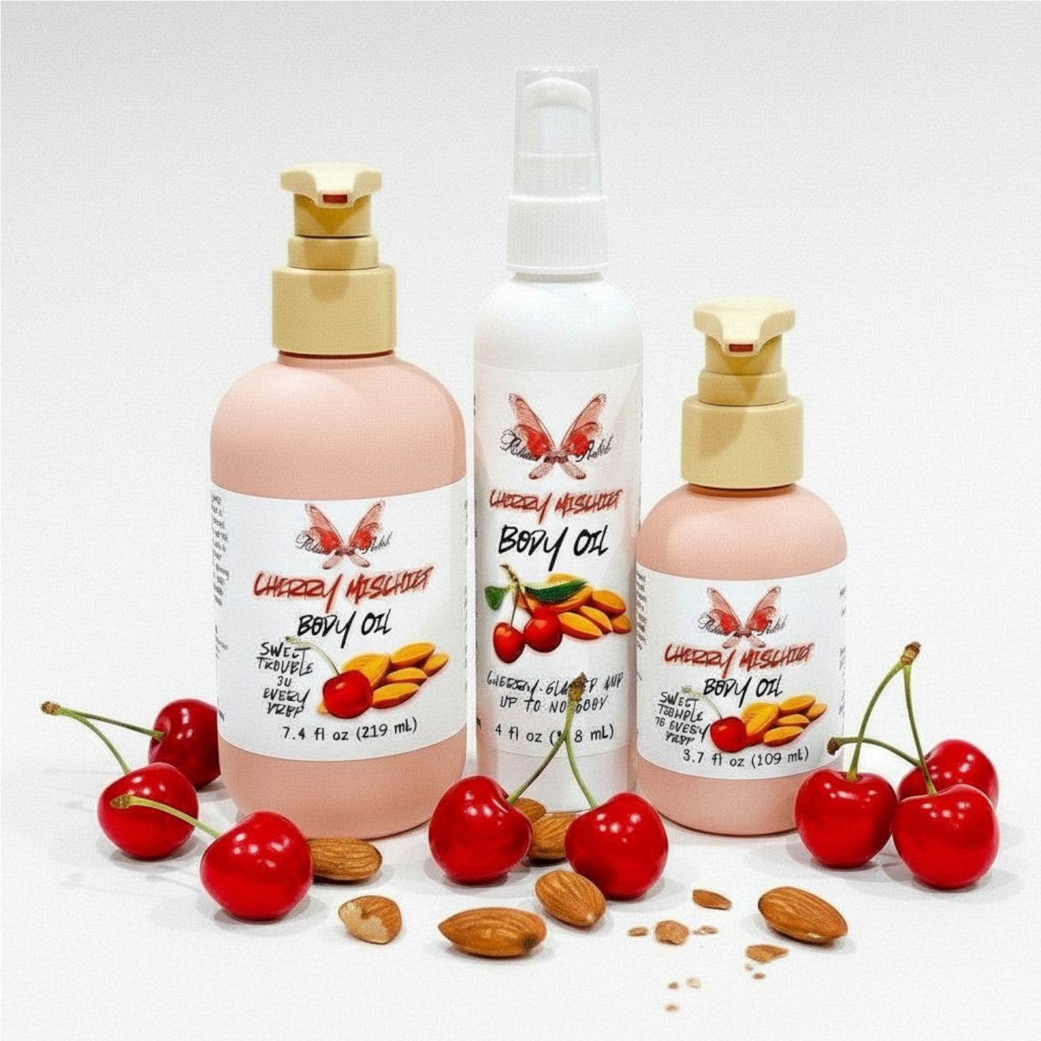 Cherry Mischief Body Oil by Ritual and Rebel 3 bottles of 7.4, 4, and 3.7 fl oz with cherry and almonds by base of bottles 