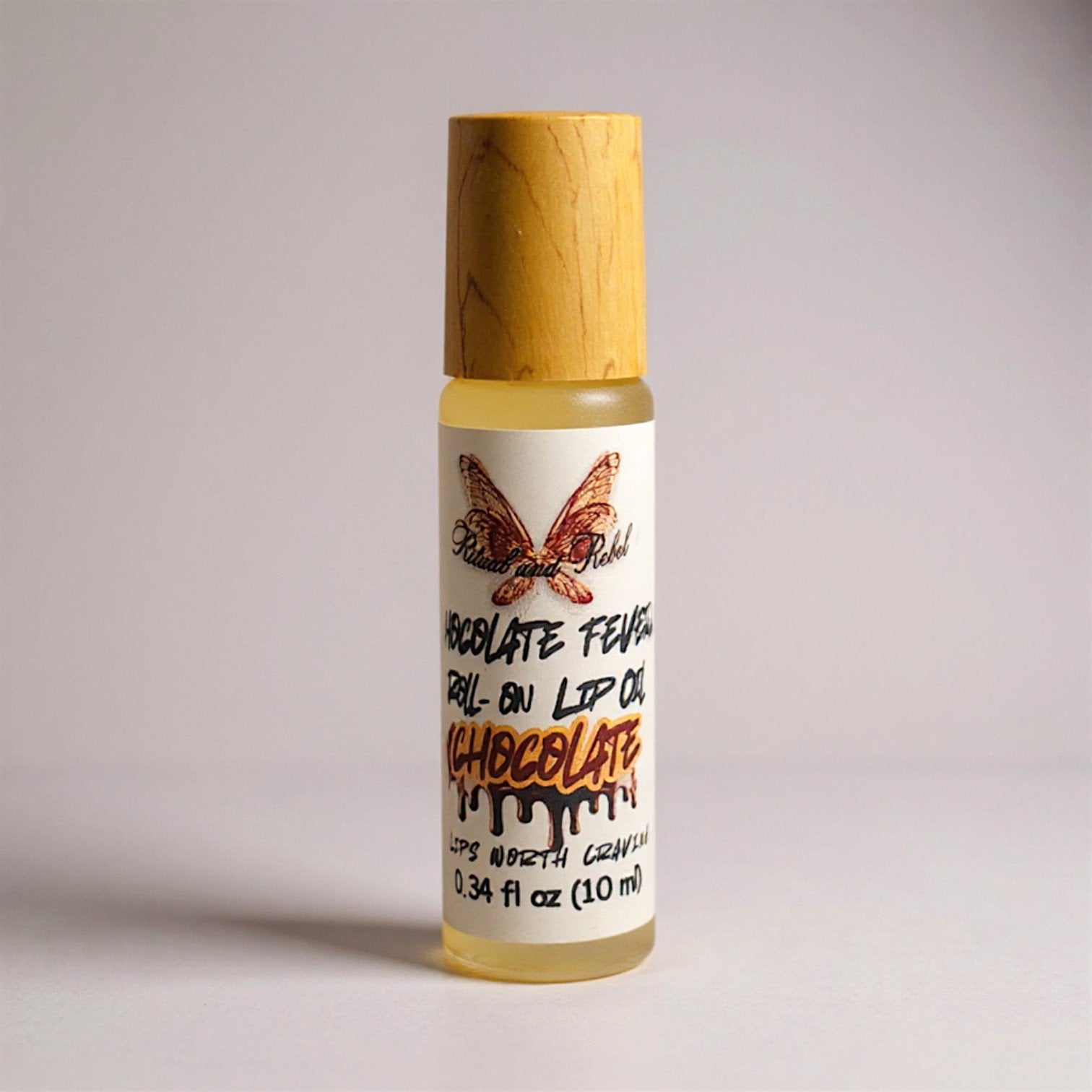 Chocolate Fever Roll-on lip oil by Ritual and Rebel glass bottle with bamboo wooden cap on a light gray background