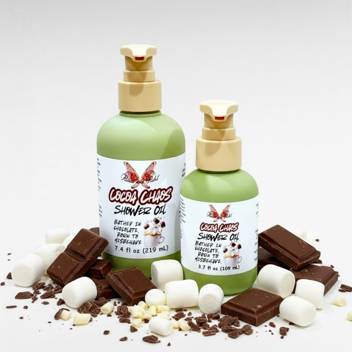 Cocoa Chaos Shower Oil by Ritual and Rebel with chocolate and marshmallow toppings on a white background with 2 green bottles with beige pumps