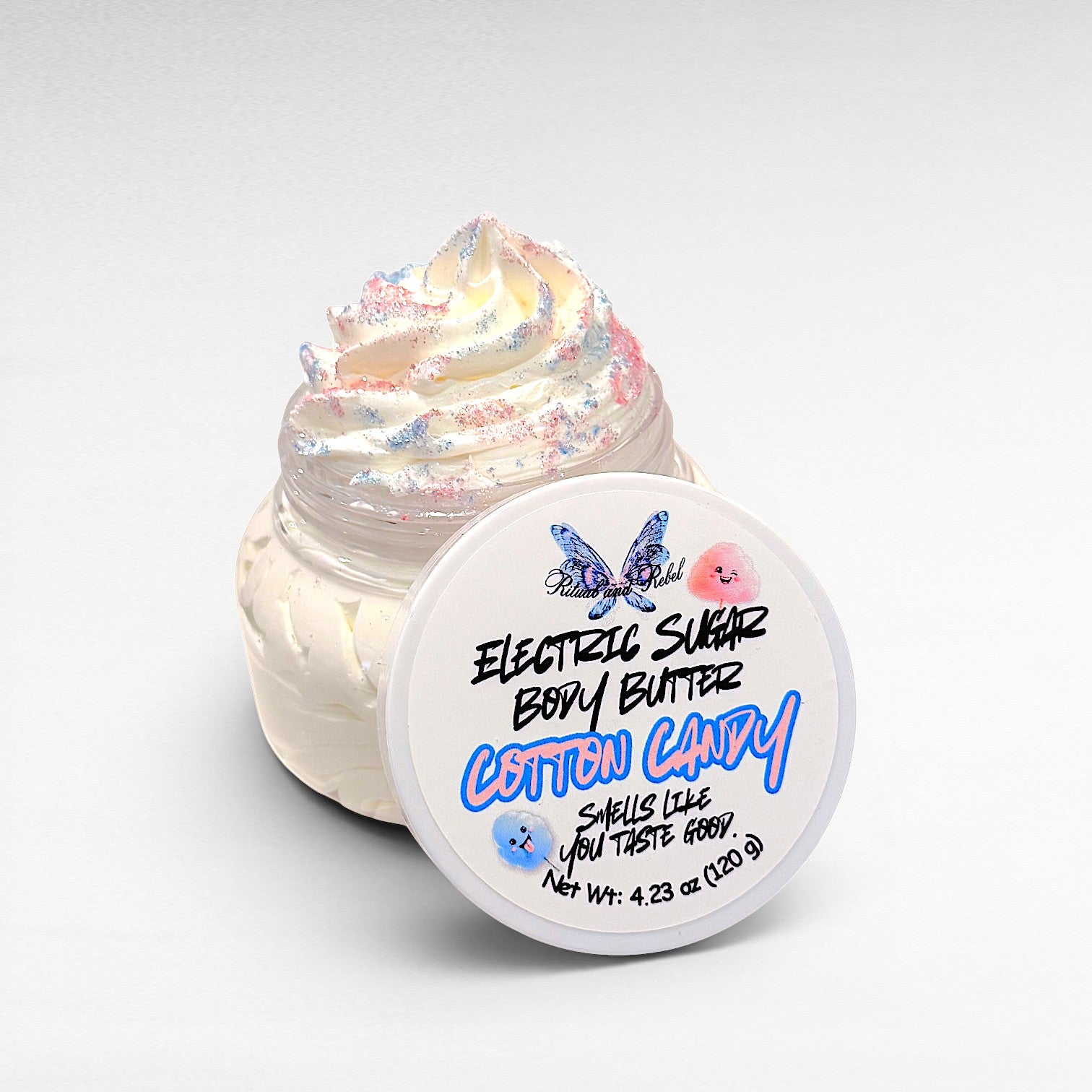 Electric Sugar Body Butter by Ritual and Rebel cream colored whipped body butter in clear plastic jar with pink and blue glitter mica on top and white round lid 4.23 oz