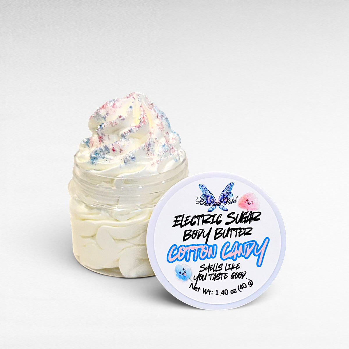 Electric Sugar Body Butter by Ritual and Rebel cream colored whipped body butter in clear plastic jar with pink and blue glitter mica on top and white round lid 1.4 oz