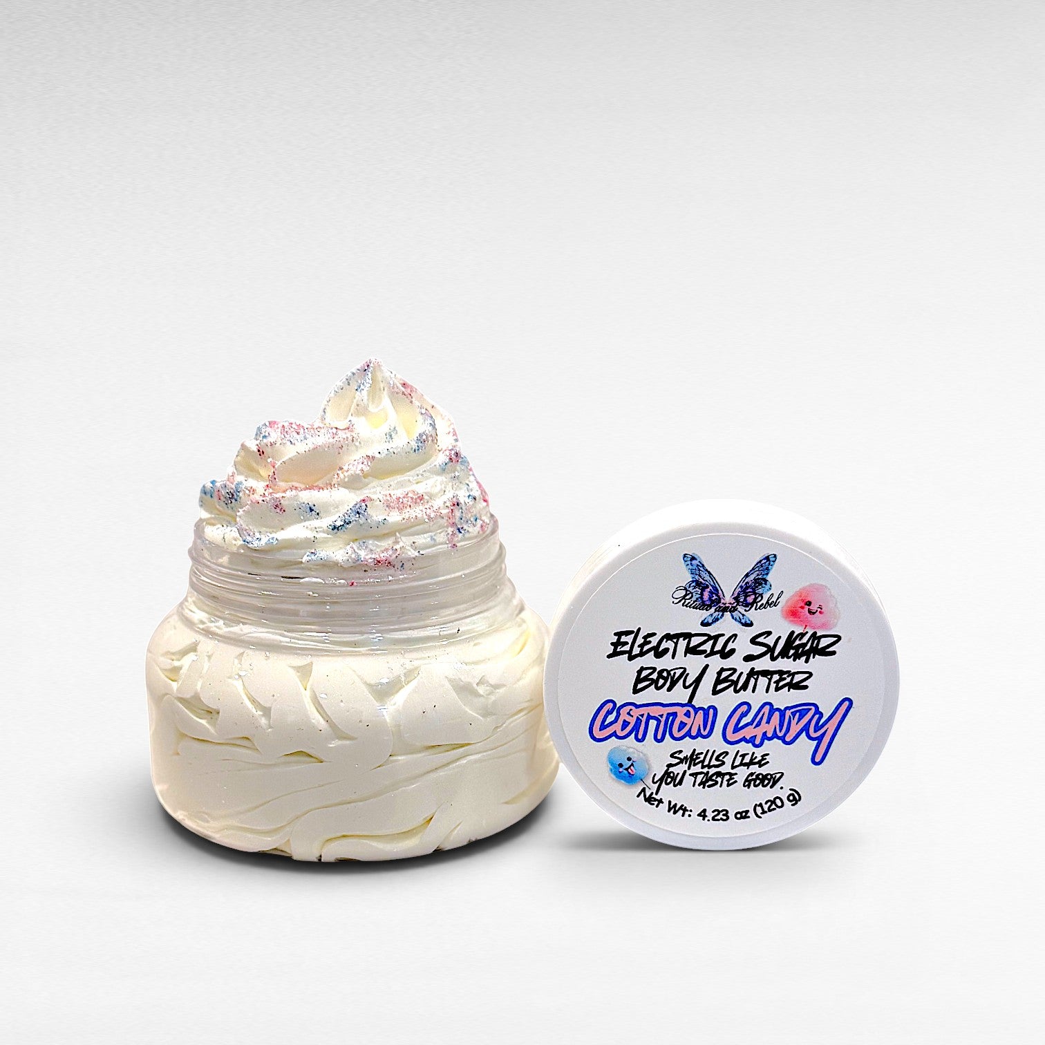 Electric Sugar Body Butter by Ritual and Rebel cream colored whipped body butter in clear plastic jar with pink and blue glitter mica on top and white round lid 4.23 oz