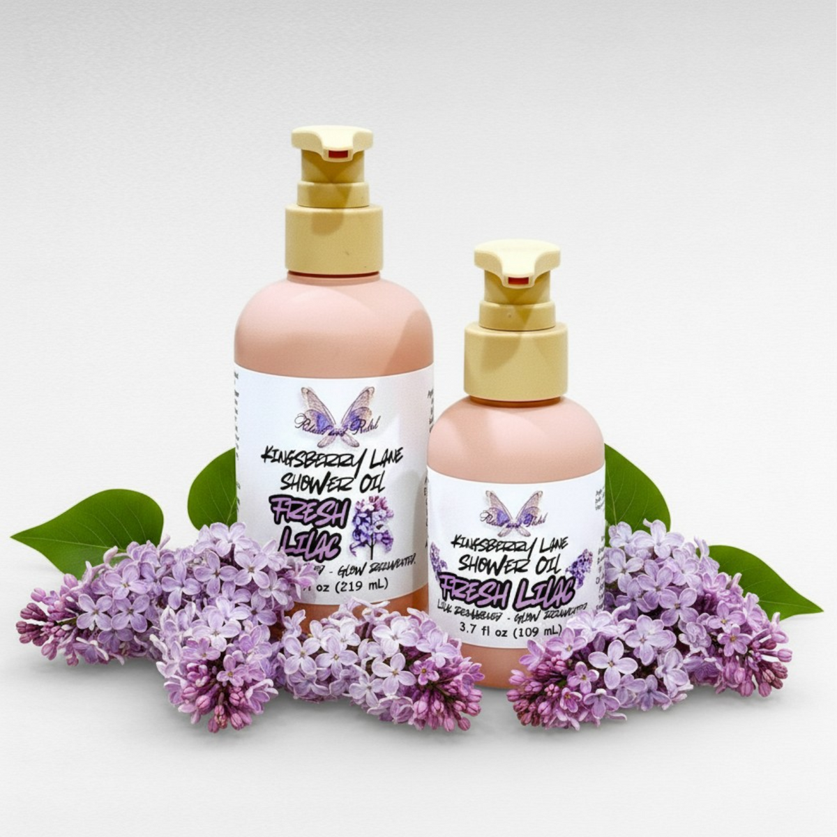 Kingsberry Lane Shower Oil by Ritual and Rebel 7.3 and 3.7 fl oz pink bottles with pumps with lilac flowers around base of bottles