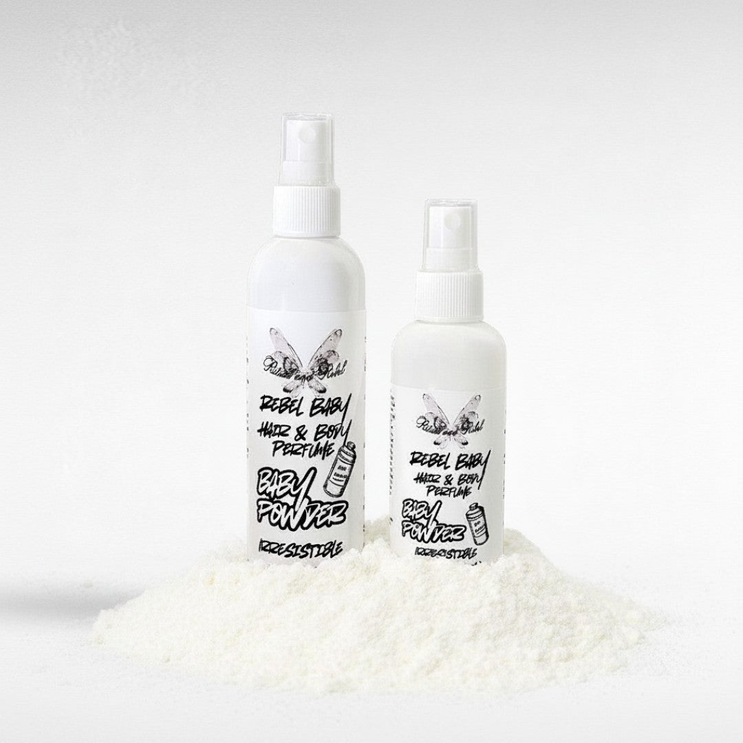 Rebel Baby Hair & Body Perfume by Ritual and Rebel 2 white spray bottles with white and black labels on a pile of baby powder. 4.4 and 3.5 fl oz