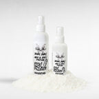Rebel Baby Hair & Body Perfume by Ritual and Rebel 2 white spray bottles with white and black labels on a pile of baby powder. 4.4 and 3.5 fl oz