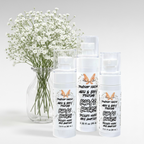 Ritual and Rebel Dewdrop Darling hair and body perfume bottles in three sizes next to a vase of white baby's breath.