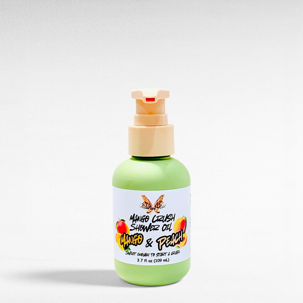 Ritual and Rebel Mango Crush Shower Oil in a green bottle with a pump dispenser, featuring mango and peach graphics.